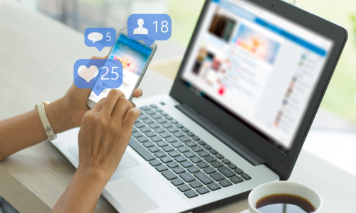 Image of laptop and mobile phone with graphics indicating social media likes.
